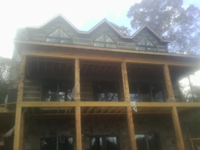 Dormers and porch framing on a large log home under construction — Roof Coating work by our crew in Matlock